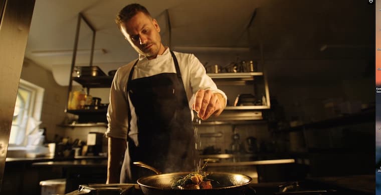 Chef seasoning a steak at Ballebro Ferry Inn